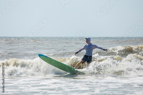 Photography Middle aged man surfing a long board on the Atlatic Ocean in South Carolina