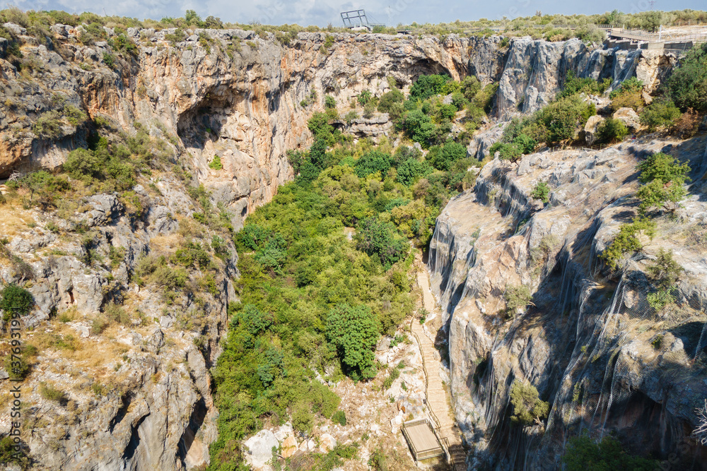 Panoramic view onto large walls & bottom of karst sinkhole called Cennet (Heaven), Kizkalesi, Turkey. It's one of biggest sinkholes in Turkey. Its depth about 70 m, square about 250x110 m