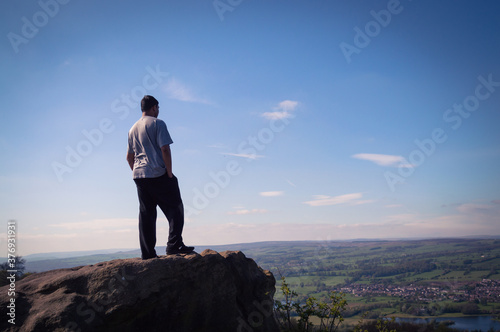 A young man climbing on rocks up the Otley Chevin, overlooking the Yorkshire village of Otley