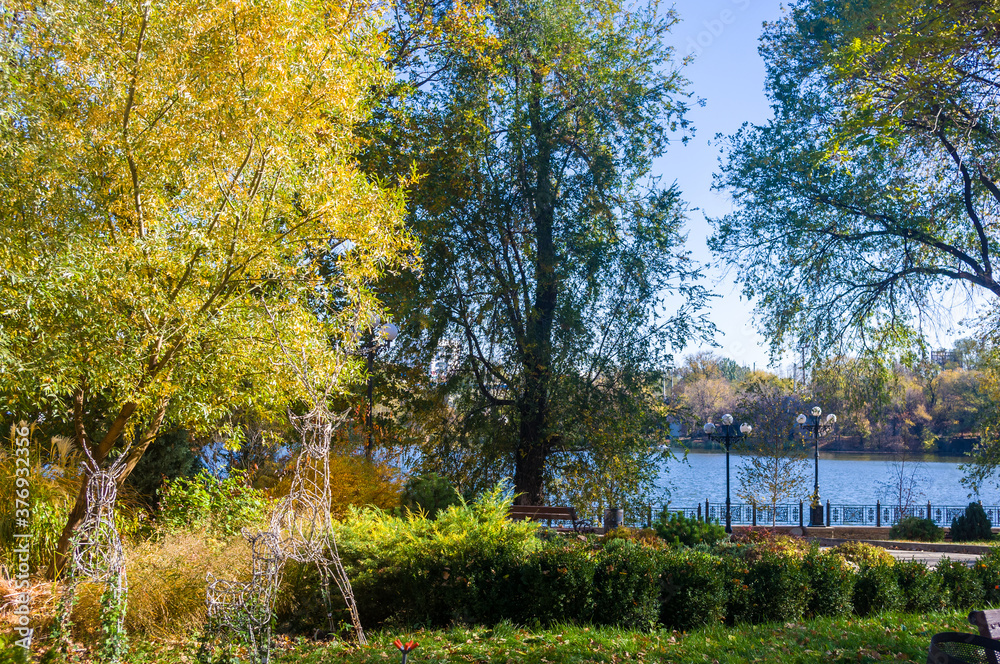 Autumn urban landscape on a Sunny day - yellow autumn trees in the Park, colorful red and orange leaves, and bright sky with clouds Autumn urban landscape on a Sunny day - yellow autumn trees in the Park, colorful red and orange leaves, and bright sky with clouds