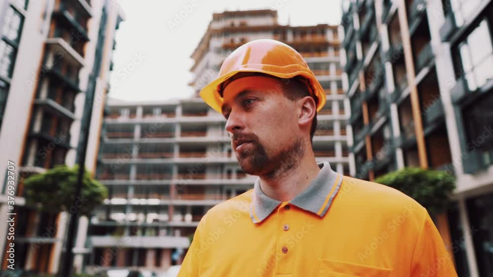 Construction site manager with expression of angry in orange uniform and helmet at construction site. Builder dissatisfied. Salary. Low wages. Hard work. Handyman. The foreman grumpy and quarrelsome Construction site manager with expression of angry in orange uniform and helmet at construction site. Builder dissatisfied. Salary. Low wages. Hard work. Handyman. The foreman grumpy and quarrelsome