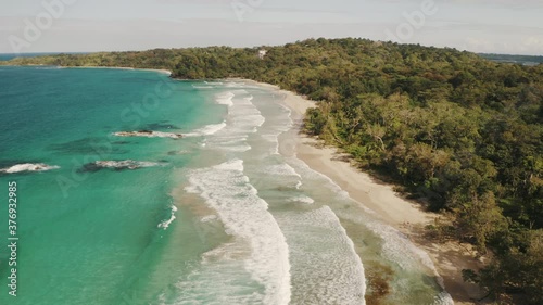 Drone video of paradise island coast with waves with views on the turquoise Caribbean ocean, white sand and jungle palm trees photo