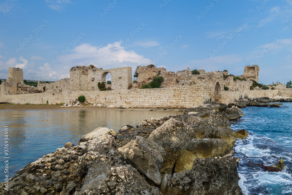Remains of stone dam, that protected bay of city Kizkalesi, Turkey. Ancient fortress Corycus is on background. It was founded as Cilician pirate base. Now citadel in UNESCO Tentative list.