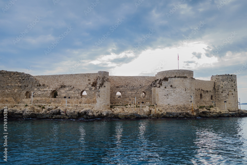 Close view onto medieval castle Kizkalesi located on island near resort city Kizkalesi, Turkey. It's main sight of this town. Powerful walls of castle was almost impregnable for siege from land & sea