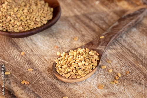 Fenugreek seeds on a wooden spoon