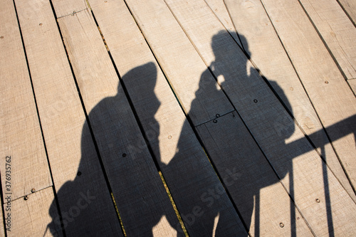 shadow of a man and woman on a wooden bridge