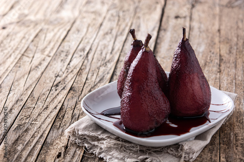 Poached pears in red wine on wooden table.Copy space
