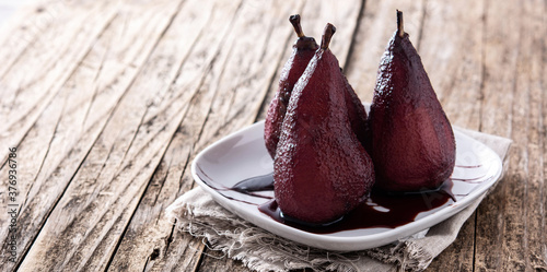 Poached pears in red wine on wooden table. Panorama view with copy space