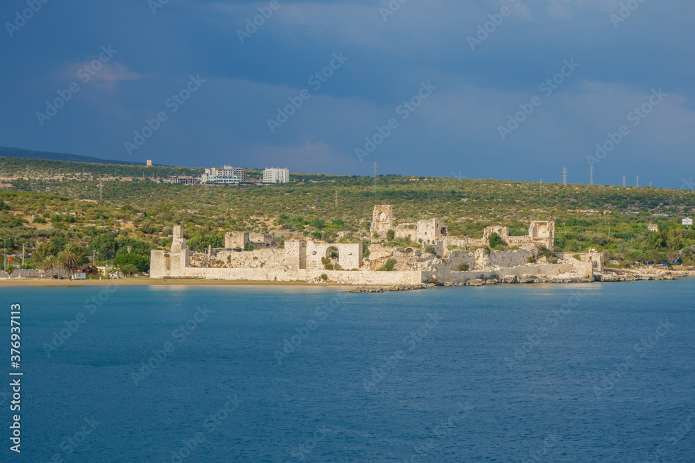 Panoramic view onto medieval fortress Corycus, Turkey. It's built on Mediterranean shoreline in ancient times. Now castle in UNESCO Tentative Heritage List. Modern city Kizkalesi on background.
