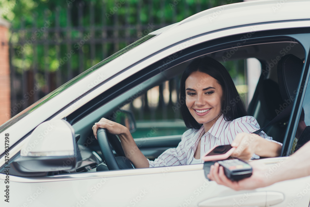 Photo of positive girl ride drive automobile hold steering wheel pay entry parking lot smartphone pos terminal in city center