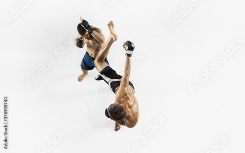 Two professional MMA fighters boxing isolated on white studio background. Top view of couple of muscular athletes. Sport, healthy lifestyle, competition, dynamic and motion, action concept. Copyspace.