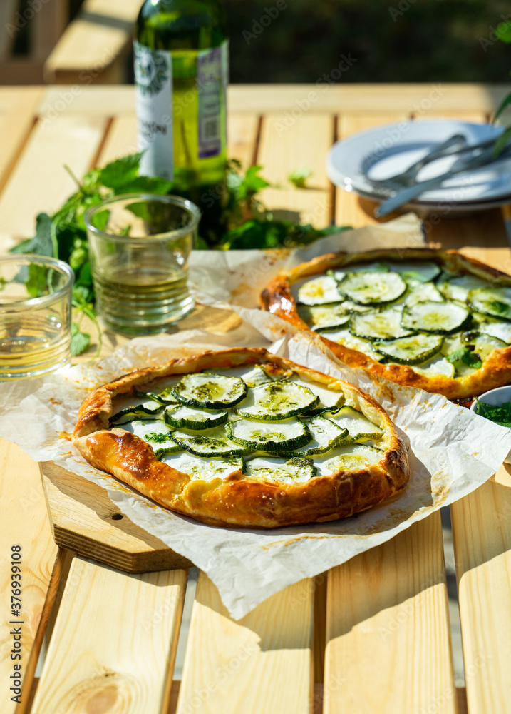 Italian cheese and zuccini galette served outdoors on a garden table with white wine. Outdoor meals concept