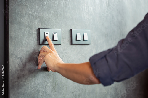 The young man's hand turned off the light switch. Energy saving concept photo