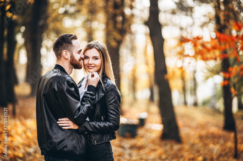 Man and woman hugging and smiling in the background of autumn park.