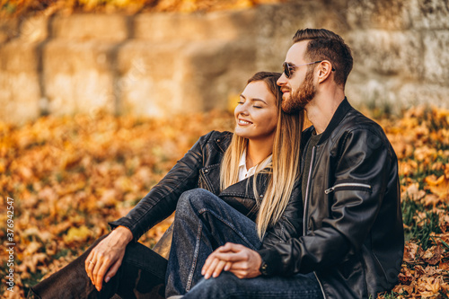 Portrait of a young loving couple, sitting in autumn leaf and enjoying nature