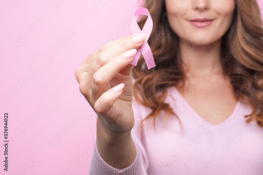 Woman in pink sweater with pink ribbon supporting breast cancer awareness campaign