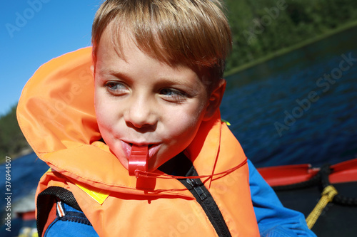 Boy with whistle in life jacket on boat photo