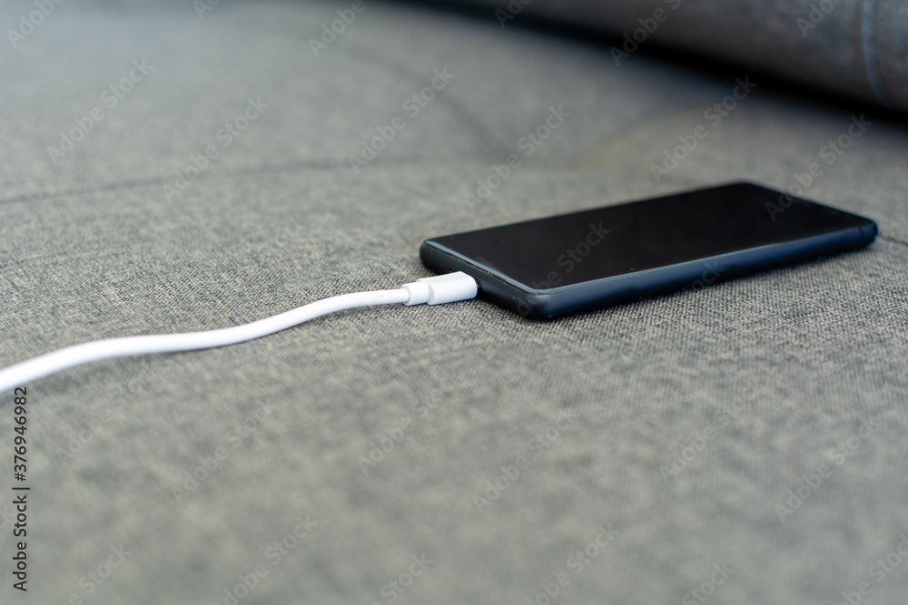 Mobile smartphone charging by sharing energy via a power bank. Tech Device Charge Sharing. Sharing technology device charge. White-colored power bank charging the black color smartphone. Mobile smartphone charging by sharing energy via a power bank. Tech Device Charge Sharing. Sharing technology device charge. White-colored power bank charging the black color smartphone.