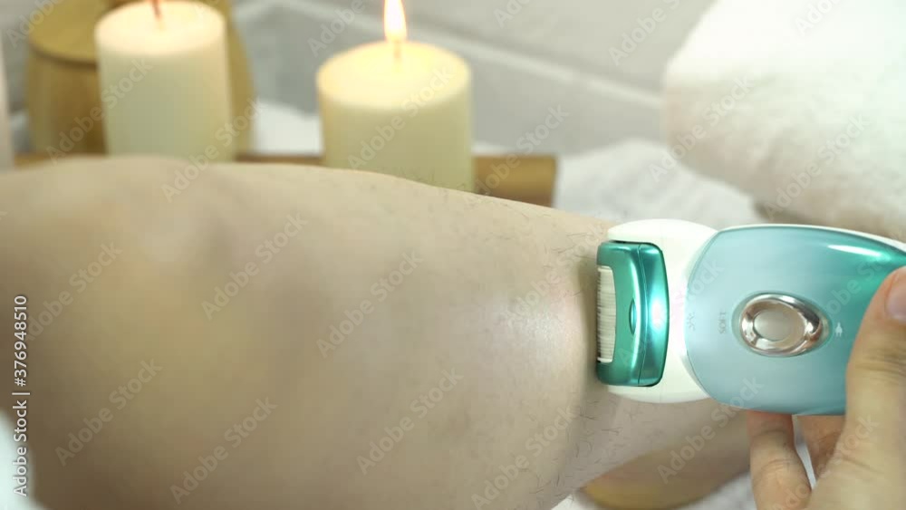 Epilation of legs at home. Young woman shaving her legs using an