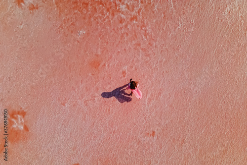 Woman walking on the surface of saline of bright pink color