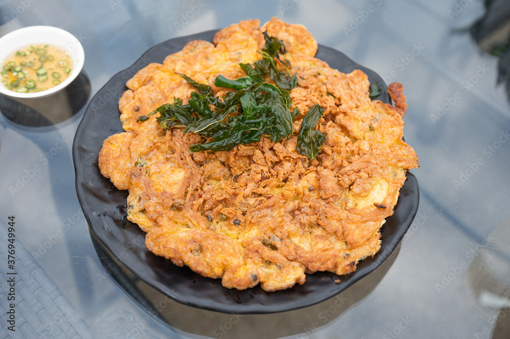 Crispy omelette with minced pork and basil leaf in black plate Crispy omelette with minced pork and basil leaf in black plate