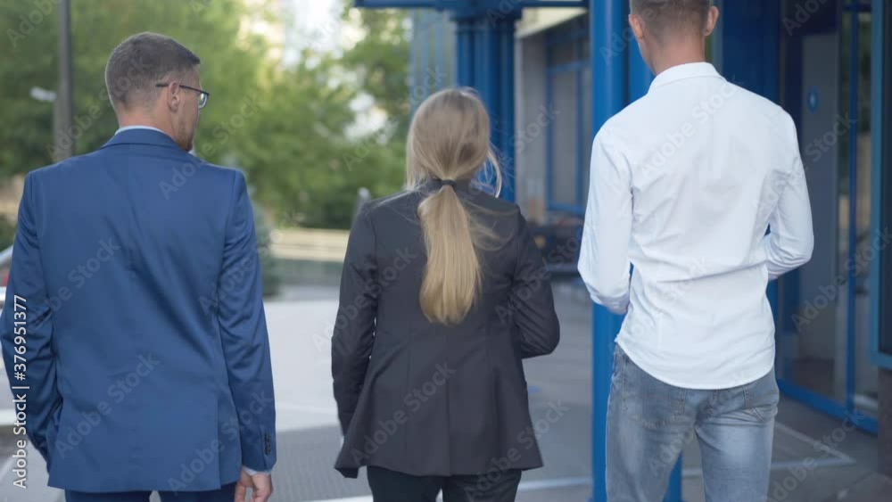 Camera follows successful Caucasian team entering business center. Back view of confident men and woman walking into building and talking. Positive colleagues returning to work after lunch. Camera follows successful Caucasian team entering business center. Back view of confident men and woman walking into building and talking. Positive colleagues returning to work after lunch.