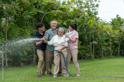 Asian family feel haapy with smil lovely are watering a tree by tube in garden at outdoor house in morning. photo