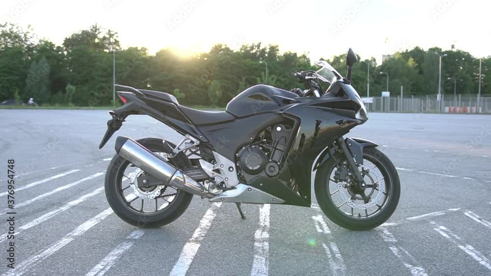 Close up of luxurious expensive black motorbike which standing on the sportground under light of sunbeams Close up of luxurious expensive black motorbike which standing on the sportground under light of sunbeams