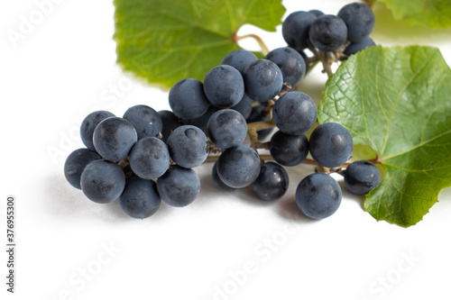 Bunch of red grapes with leaves on a white background