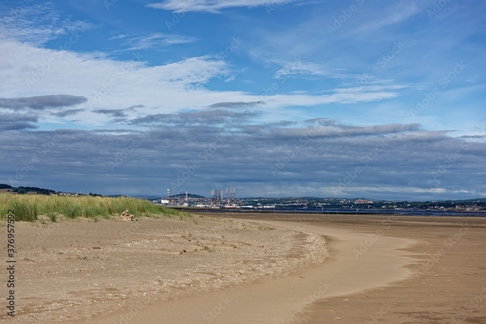 Oil Rigs in for a Refit at the port of Dundee seen from Tentsmuir Point and its gently shelving Beach at Low tide on a sunny day in August.