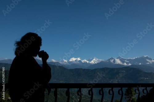 The mighty Kanchanjunga with other snow peaks at the background of a small village on the slope of mountains on the Himalaya from the balcony of a tourist cottage in Sikkim photo