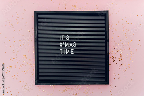 Christmas time words on letterboard on pink background with glitter confetti. photo