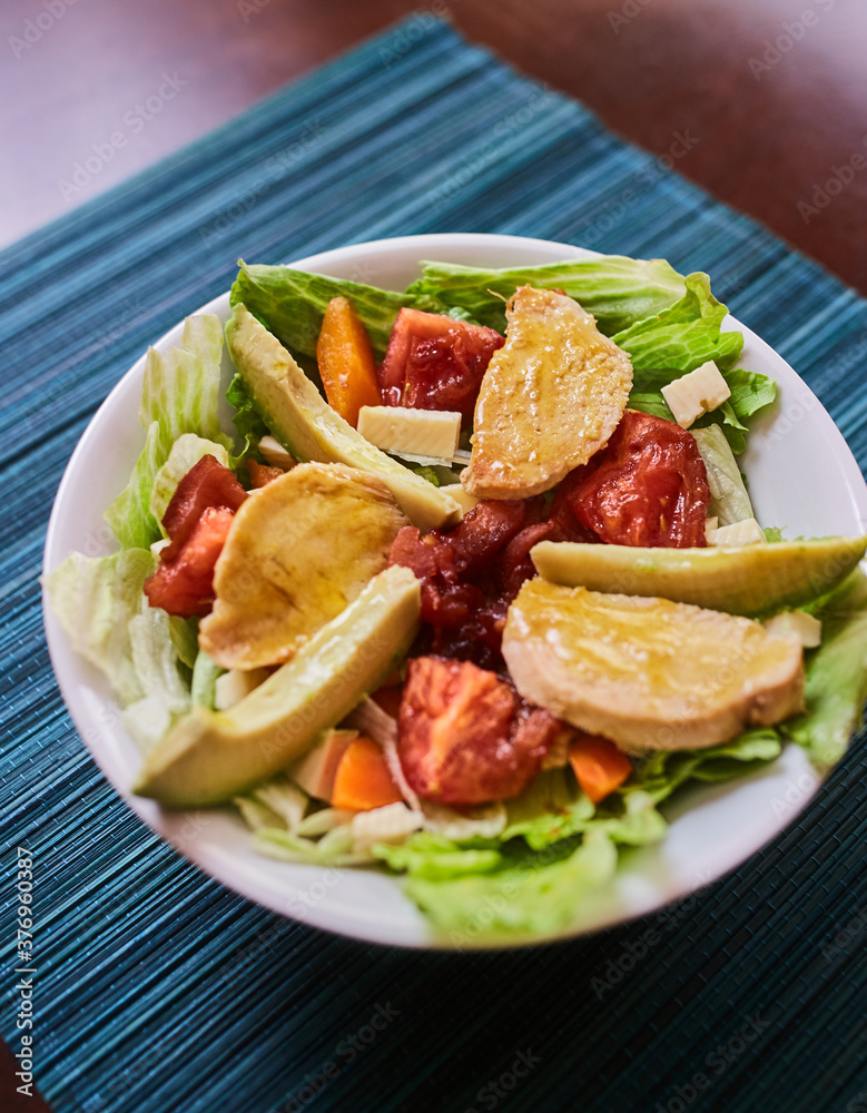 Ensalada de lechuga con tomates, pollo, palta, queso, zanahoria y queso. Vinagreta dulce. Fondo de textura turquesa Ensalada de lechuga con tomates, pollo, palta, queso, zanahoria y queso. Vinagreta dulce. Fondo de textura turquesa