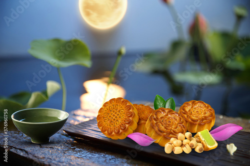 Chinese lanterns and full moon over night river for mid-autumn festival poster. Table with mooncakes and cup of tea, chopsticks and lotus, vietnam