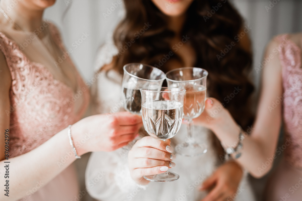 Photo bride with her friends drinking champagne from glasses