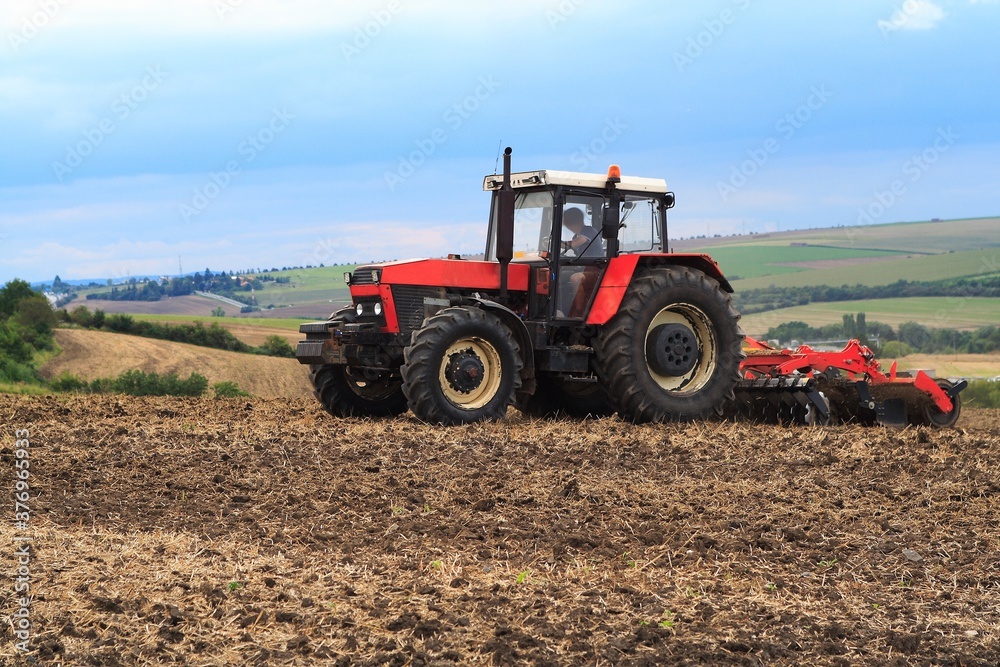 Red retro tractor on the field during autumn work, on the background of the horizon Red retro tractor on the field during autumn work, on the background of the horizon