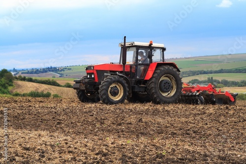 Red retro tractor on the field during autumn work  on the background of the horizon