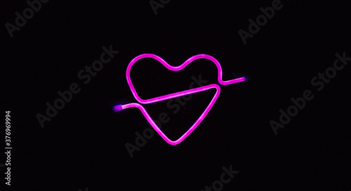 Bright luminous digital neon sign for a store or card beautiful shiny with a love heart pierced by cupid arrow. Glowing amour shape symbol passion in vivid colors. Valentines day concept.