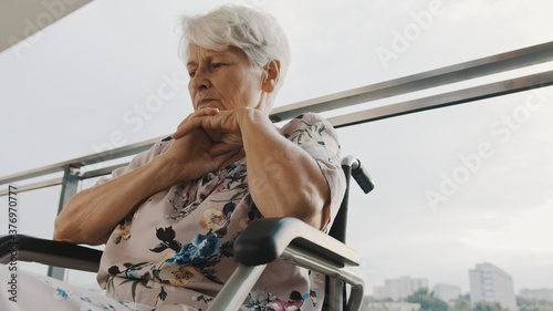 Pensive sick disabled old lady sit in wheelchair look in distance feel lonely at home or retirement house. High quality photo