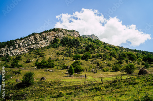 Picturesque scenery. Mountain against cloudy sky. Clouds floating on blue sky over mountain ridge.