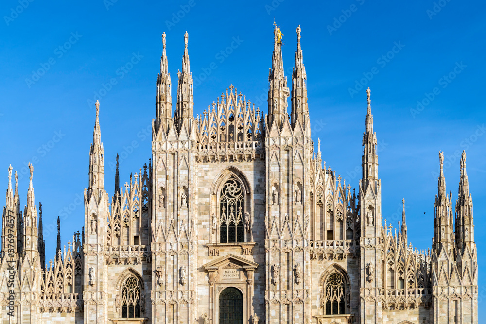 Facade of the Cathedral of Milan with blue sky and statues pillars Facade of the Cathedral of Milan with blue sky and statues pillars