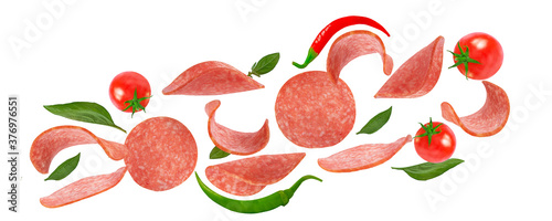 salami slices, tomatoes and basil on a white background