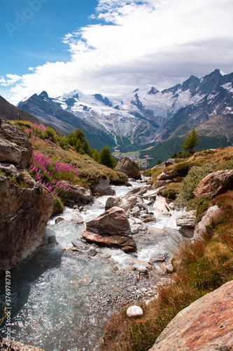 Beautiful mountain landscape with stream near Alps, Switzerland in the summer in blue sky