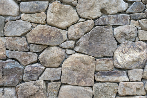 Gray stone blocks with gaps placed on the cement wall, texture, background 