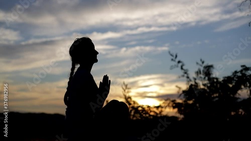 Silhouette of a young woman practicing yoga in a city park photo