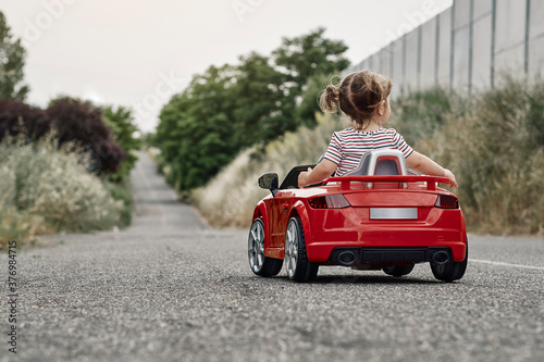 A girl riding a toy car photo