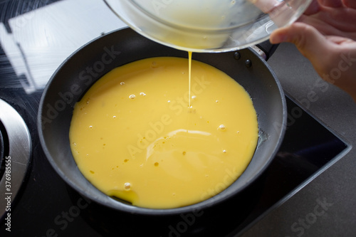 Pouring beaten eggs into a frying pan photo