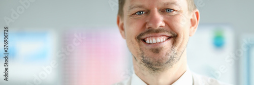 Close-up of smiling middle-aged businessman wearing presentable suit. Copy space in left side. Macro shot of happy employee with shining smile. Business company concept