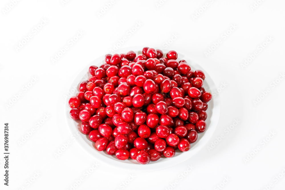 Red cherries on a white plate on a white background Red cherries on a white plate on a white background