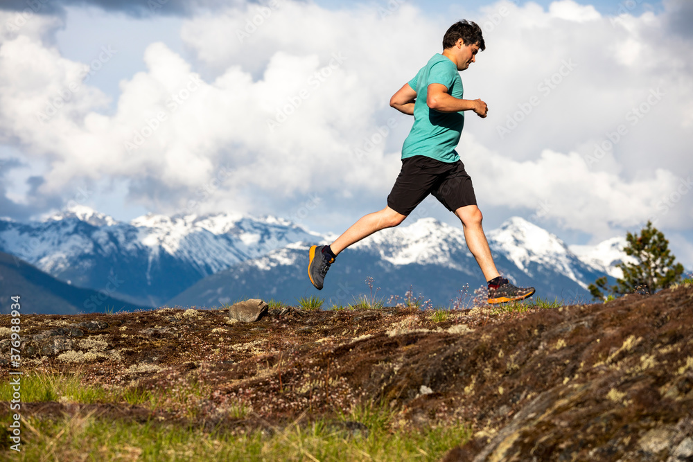 Man trail runs on a scenic alpine mountain trail in British Columbia. Man trail runs on a scenic alpine mountain trail in British Columbia.